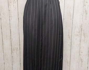 May include: Black pencil skirt with vertical white pinstripes. The skirt has a high waist and a button closure. The fabric appears to be a lightweight material, suitable for warmer weather. The skirt is knee-length.