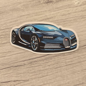May include: A blue and black Bugatti Chiron sports car sticker. The car is facing forward and has a black grille and headlights. The sticker is on a light brown wooden surface.