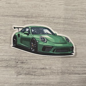 May include: A green Porsche 911 GT3 RS sports car sticker. The car has a black rear wing and black wheels.
