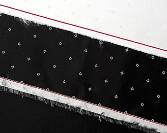 May include: A close-up of a black and white fabric with a red line. The fabric has a small, white dot pattern.