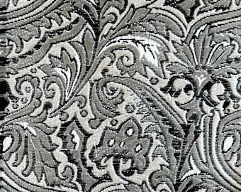May include: A silver and black fabric with a repeating floral pattern. The fabric has a textured, woven look.