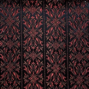 May include: Black fabric with a repeating pattern of red and gold floral designs. The fabric has a textured, woven look.