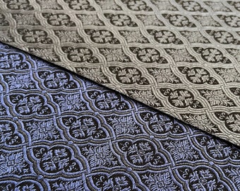 May include: A close-up of two fabric swatches with a repeating geometric pattern. The top swatch is a light gray with a black pattern, and the bottom swatch is a dark blue with a black pattern.