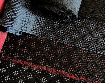 May include: Close-up of four different black fabrics with various textures. The top fabric is a smooth, black satin. The second fabric is a black fabric with a subtle, woven pattern. The third fabric is a black fabric with a red and white checkered pattern. The bottom fabric is a black fabric with a small, square pattern.