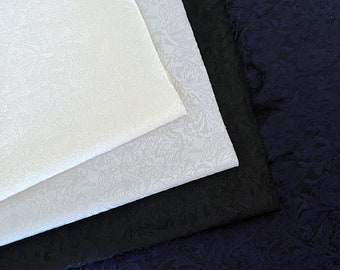 May include: Four pieces of fabric, two white, one black, and one dark blue, all with an embossed floral pattern.