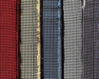 May include: Close-up of fabric swatches in various colors and patterns, including red, white, black, blue, and gray. The fabric has a textured, woven look.
