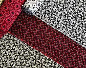 May include: Four rolls of fabric with different geometric patterns. The fabric is black with a white or red pattern. The patterns are all similar, but have slight variations.