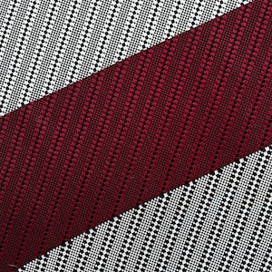 Puede incluir: Primer plano de una tela con un patrón diagonal de cuadrados negros y blancos. Una banda diagonal de tela burdeos con un patrón similar se superpone a la tela negra y blanca.
