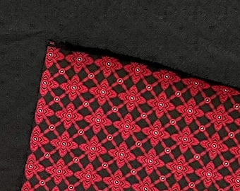 May include: Red and black fabric with a repeating geometric pattern. The pattern features small red flowers with white centers and black outlines, arranged in a grid.