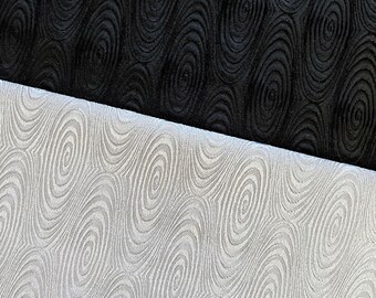 May include: Two fabric swatches with a swirling oval pattern. The top swatch is black and the bottom swatch is white.