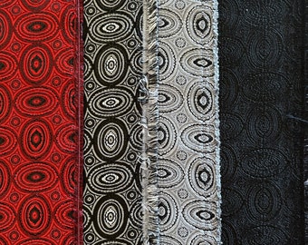 May include: Four fabric swatches with different patterns. The first swatch is red with a black and white pattern. The second swatch is black with a white and gray pattern. The third swatch is gray with a white and black pattern. The fourth swatch is black with a gray pattern.