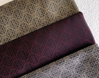 May include: Three fabric swatches with a geometric pattern. The top swatch is black with gold accents, the middle swatch is burgundy with gold accents, and the bottom swatch is black with gold accents.