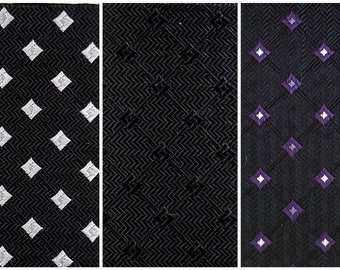 May include: Three black neckties with different patterns. The first tie has a white diamond pattern. The second tie has a herringbone pattern. The third tie has a purple and white diamond pattern.