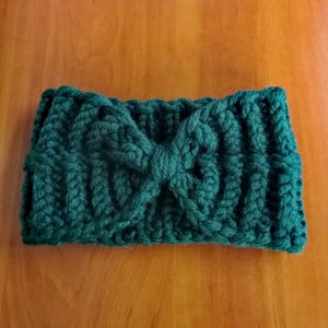 May include: A dark green knitted headband with a large bow in the center.