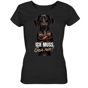 May include: Black t-shirt with a dachshund dog wearing a serious expression and crossed arms. The text "ICH MUSS Gar nix!" is printed on the shirt.