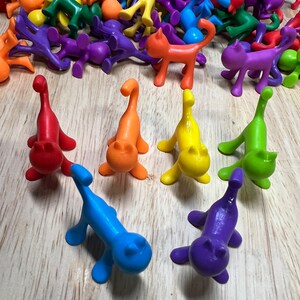 Peut inclure: Un ensemble de figurines de chat en plastique coloré. Les chats sont dans différentes poses et sont faits d'un plastique lisse et brillant. Les couleurs incluent le rouge, l'orange, le jaune, le vert, le bleu et le violet.