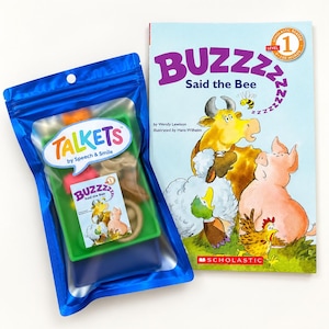 May include: A blue plastic pouch labelled Talkets by Speech & Smile containing small colourful items and a miniature book cover, alongside a Scholastic Level 1 reader book titled BUZZZZ Said the Bee featuring illustrations of a cow, pig, duck, and chicken.
