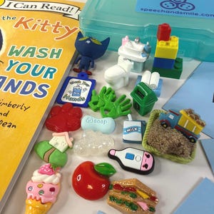 May include: A collection of colorful, miniature toy figures and accessories, including a book titled "The Kitty Wash Your Hands". The toys include a blue cat figure, a miniature toilet, a stack of blocks, and a toy train.