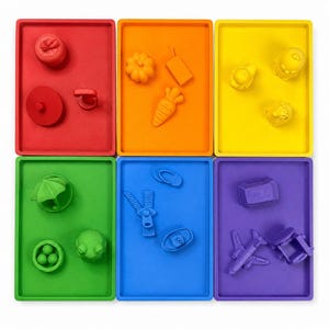 May include: Six rectangular trays in red, orange, yellow, green, blue, and purple, each containing small monochromatic objects. The red tray holds a fruit, circle, and handle. The orange tray features a pumpkin, juice box, and carrot shapes.