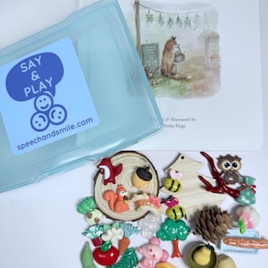 May include: A blue plastic container with a sticker that says "Say & Play" and a website address. The container is open and there are many colourful plastic figurines inside, including a squirrel, a bee, a pine cone, a pear, a strawberry, and a tomato.