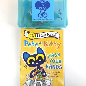 May include: A children's book titled "Pete the Kitty Wash Your Hands" with a cartoon cat illustration. Above it is a clear blue plastic box with a "Say & Play" sticker and the website speechandsmile.com.