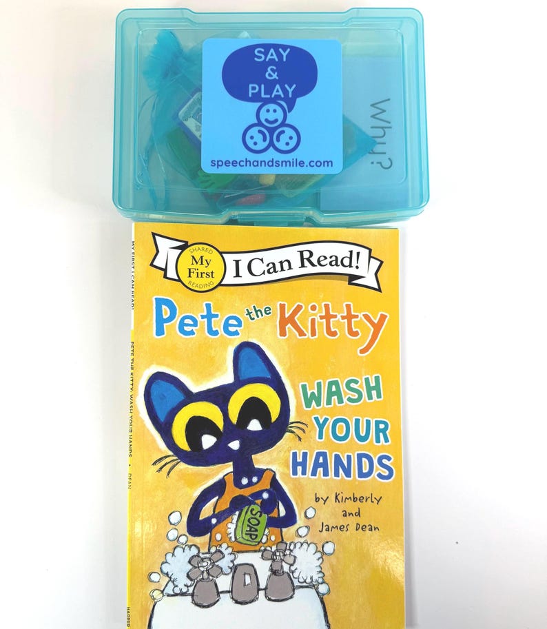 May include: A children's book titled "Pete the Kitty Wash Your Hands" with a cartoon cat illustration. Above it is a clear blue plastic box with a "Say & Play" sticker and the website speechandsmile.com.