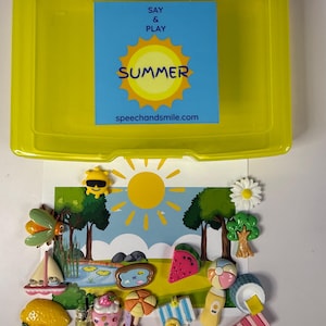 May include: A yellow plastic container with a blue and yellow label that reads "SAY & PLAY SUMMER" and "speechandsmile.com". Inside are various summer-themed decorative items, including a lemon, ice cream cone, and watermelon.