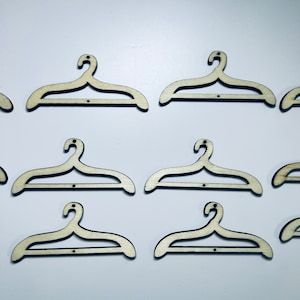 Peut inclure: Dix cintres en bois de couleur brun clair. Les cintres sont tous de la même taille et de la même forme, et ils sont disposés en rangée.