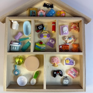 Peut inclure: Une étagère en bois en forme de maison remplie de jouets miniatures et d'objets décoratifs. Comprend une chauve-souris, un cadre photo, une baignoire, un livre, un cheval à bascule, une télévision et une manette de jeu.