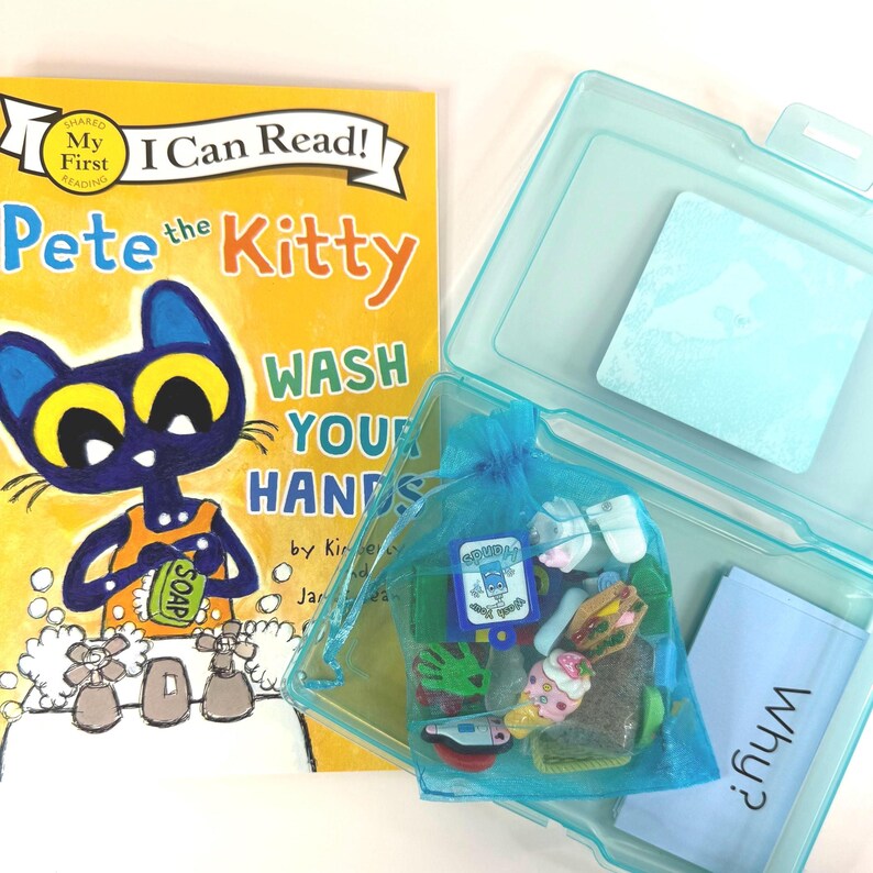 May include: A children's book titled "Pete the Kitty Wash Your Hands" with a blue kitty illustration. A clear plastic case contains a blue drawstring bag filled with small toys and a small blue card with the word "Why?" printed on it.
