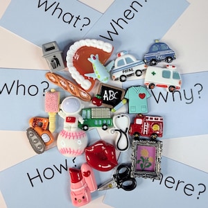 Może przedstawiać: Kolekcja kolorowych, miniaturowych przedmiotów, w tym radiowóz, karetka i wóz strażacki, ułożonych z kartami z napisami "What?", "When?", "Who?", "Why?", "How?" i "Where?". Inne przedmioty to kawałek pizzy, astronauta i szminka.
