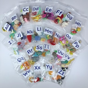 Pode incluir: Uma coleção de vinte e seis sacos de plástico transparentes e seláveis, cada um rotulado com um par de letras maiúsculas e minúsculas de Aa a Zz. Cada saco contém uma variedade de pequenos berloques e figuras de plástico coloridas.