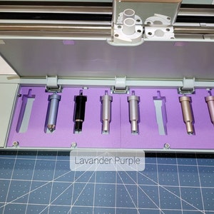 Pode incluir: Um close-up de uma bandeja de espuma roxa com seis l&acirc;minas de corte de diferentes cores para uma m&aacute;quina de corte artesanal. As l&acirc;minas s&atilde;o etiquetadas como "Lavender Purple".