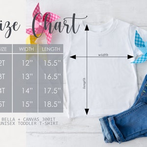 May include: White unisex toddler t-shirt with a size chart. The chart shows measurements for sizes 2T to 5T, with widths from 12" to 15" and lengths from 15.5" to 18.5". The shirt is paired with blue jeans and decorative pinwheels.