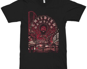 May include: A black short-sleeve t-shirt featuring a red graphic print of a carnival scene. The design includes a Ferris wheel with the text Childish Gambino, and signs reading This Is Tour America, Wells Fargo Center, and Philadelphia PA.