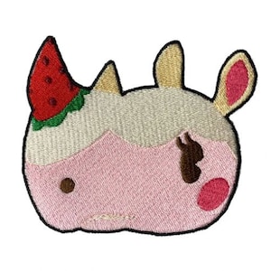 May include: Embroidered patch featuring a cartoon cow head with a watermelon slice on its head. The patch has a pink face, tan and pink ears, and a brown spot. The patch is outlined in black.