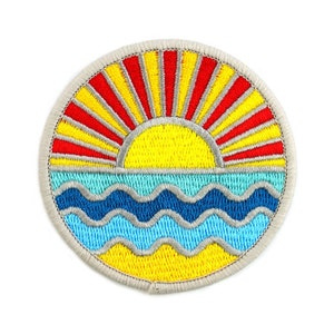 Peut inclure: Écusson brodé représentant un lever de soleil sur des vagues océaniques. Le soleil est jaune avec des rayons rouges et jaunes. Les vagues sont bleues et jaunes, avec une bordure bleu clair. L'écusson a une bordure grise.