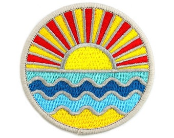 May include: Embroidered patch featuring a sunrise over ocean waves. The sun is yellow with red and yellow rays. The waves are blue and yellow, with a light blue border. The patch has a gray border.