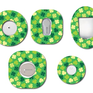 May include: A collection of green and yellow clover-patterned adhesive patches in various shapes. The patches are designed to fit around medical devices, with cutouts for sensors and displays. The overall theme is St. Patrick's Day.