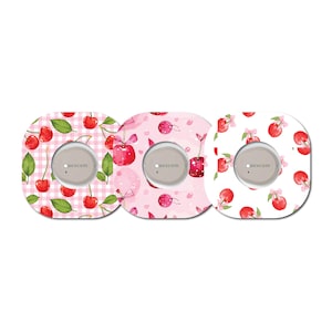 May include: Three square stickers with a cherry pattern. The stickers are pink, white, and pink with white polka dots. Each sticker has a round, gray area with the word "Dexcom" printed in white.