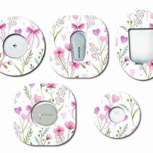 May include: Five adhesive patches for medical sensors featuring a white background with a pattern of pink flowers, green stems, pink bows, and small purple hearts. The patches vary in shape, including circular and rounded rectangular designs.