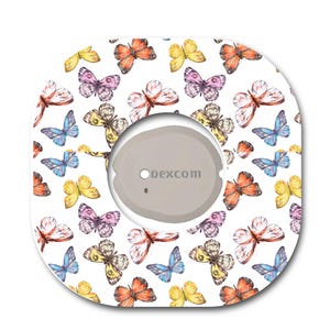 May include: A square adhesive patch with rounded corners featuring a white background and a repeating pattern of colorful butterflies in shades of orange, yellow, blue, and purple. A circular gray Dexcom device is centered on the patch.