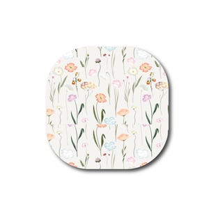 May include: A square-shaped tile with rounded corners featuring a repeating pattern of delicate wildflowers in shades of peach, light blue, lavender, and white on a cream background, with thin green stems and leaves scattered across the surface.