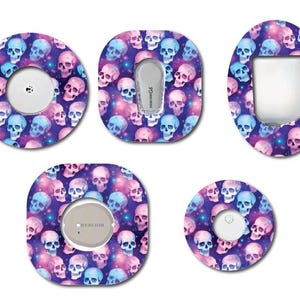 Peut inclure: Ensemble de protections pour dispositifs médicaux avec un motif de crânes bleus, roses et violets sur fond étoilé. Les protections sont de formes et tailles variées, pour dispositifs médicaux.