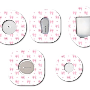 May include: Five different adhesive patches with a white background and a pink bow pattern. The patches are designed to cover medical devices.