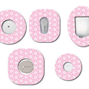May include: Five different sized adhesive stickers with a pink background and white daisy pattern. The stickers are designed to cover medical devices.