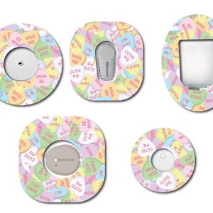 May include: Five round and oval shaped adhesive stickers with a candy heart design. The stickers feature a variety of colors, including pink, yellow, green, and blue. The stickers have a white background and feature a variety of phrases, including "Kiss Me", "Cutie Pie", "I'm Shy", "Be Mine", and "Cupcake".