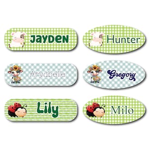 May include: Six oval-shaped personalized name labels with a green and white checkered background. Each label features a different animal illustration: a cow, a ladybug, and a sunflower. The names on the labels are Jayden, Hunter, Aryabelle, Gregory, Lily, and Milo.