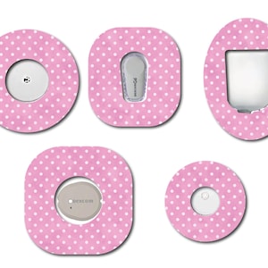 May include: A collection of pink adhesive patches with white polka dots, designed to cover medical devices. The patches are in various shapes, including circles, squares, and ovals, each with a central opening to accommodate the device.