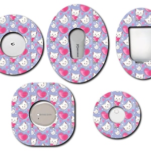 May include: A collection of five patterned medical device covers. Each cover features a repeating pattern of white cartoon cats holding pink hearts on a light purple background. The covers are in various shapes, including circles and ovals.